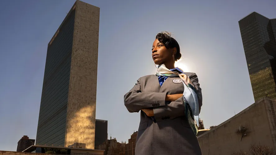 A student standing with her arms crossed in front of her, with the United Nations headquarters behind her.
