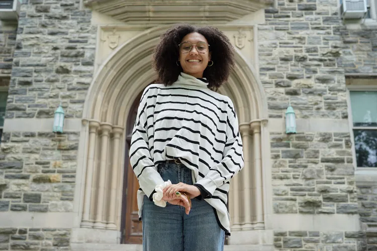 A student poses outside of a building on campus