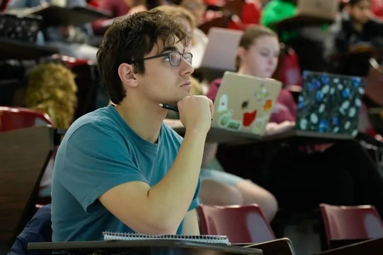 Student looks up during a class with several students on laptops behind him.