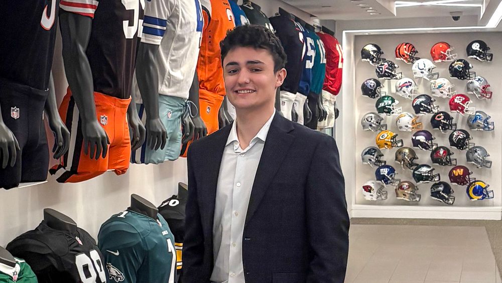 Chris Orlando poses in front of a wall of memorabilia in the NFL Offices