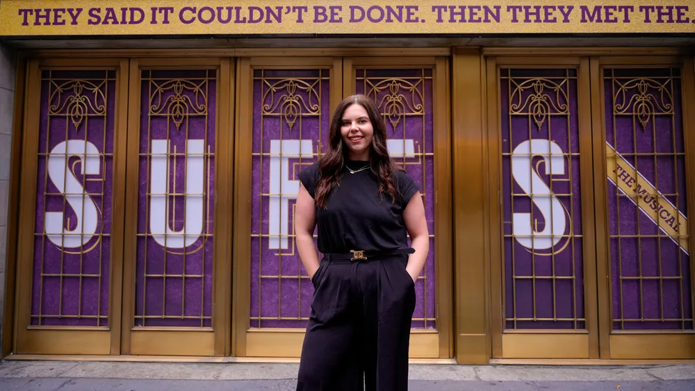 Morgan Steward standing in front of the theatre where Suffs is playing