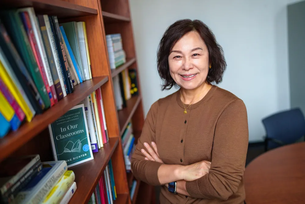 Su-Je Cho stands beside a book shelf in her office