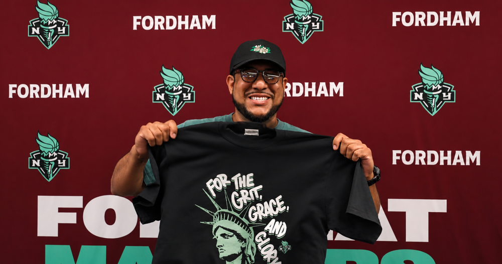 Brooklyn artist Josh Zepeda holds up a t-shirt he designed for Fordham Day at the New York Liberty