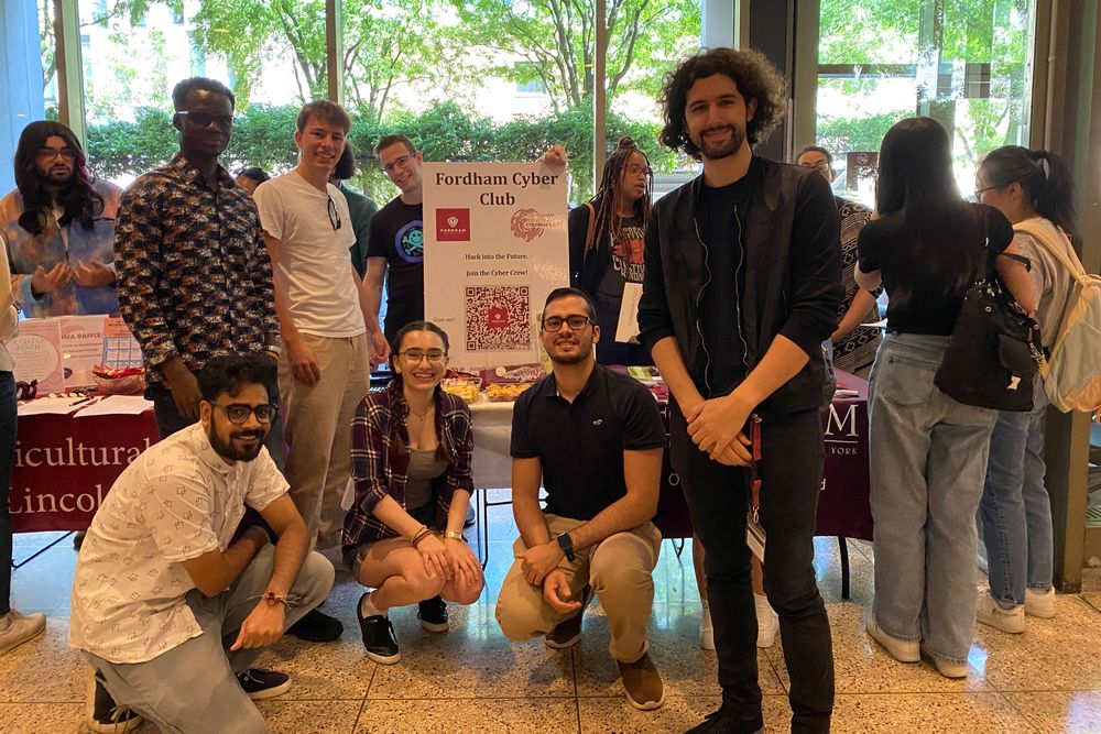 A diverse group of Cyber Club members pose in front of their table at the Lincoln Center club fair