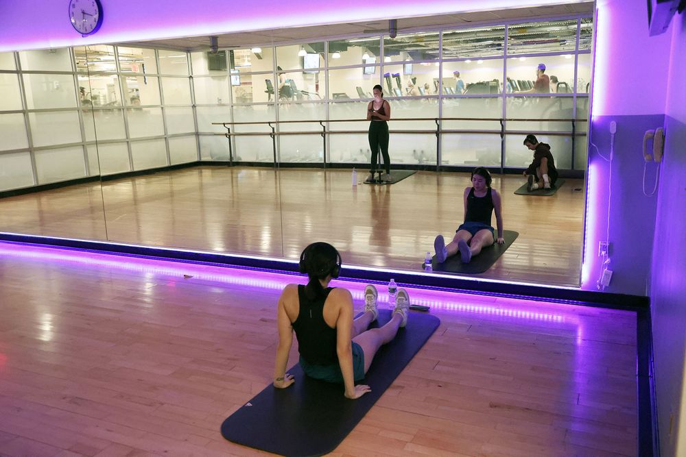 A student stretches on a mat in the yoga studio in the RamFit Center at Rose Hill