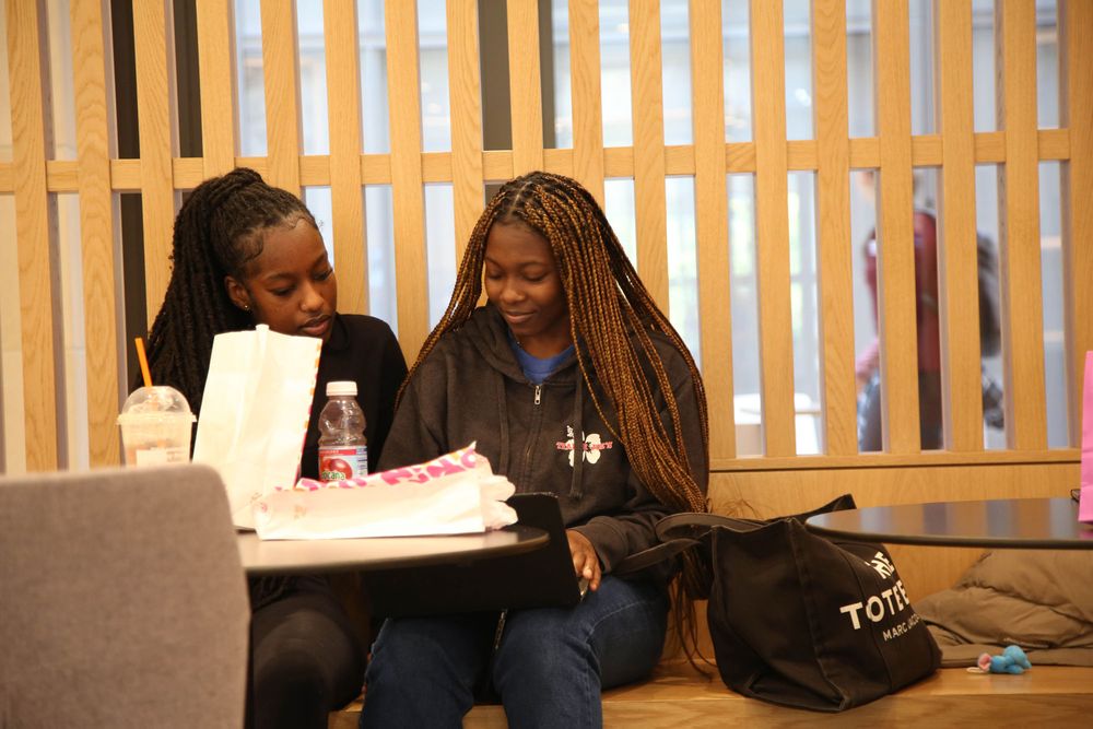 Two female students eat some Dunkin Donuts while studying in the McShane Center at Rose Hill