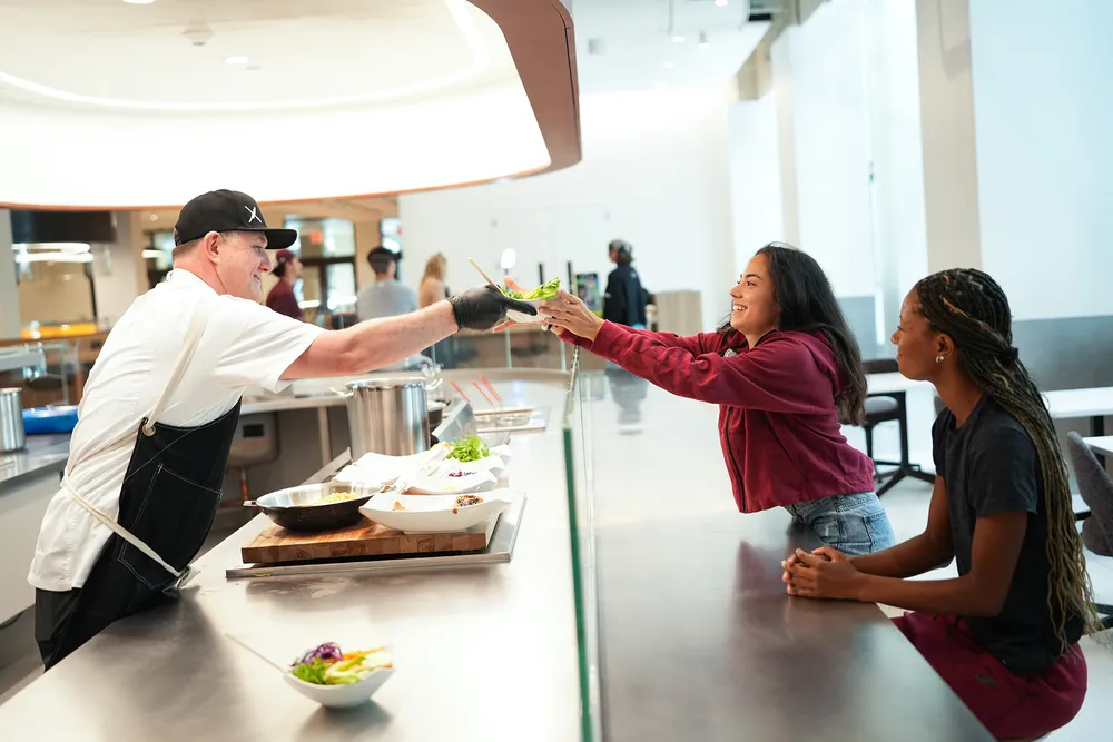 Chef creating and serving dishes to students