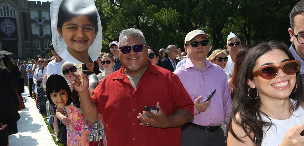 Graduate's family holding a face sign at university commencement