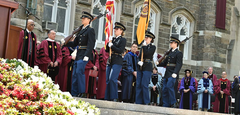 Members of ROTC holding flags on stage at University Commencement