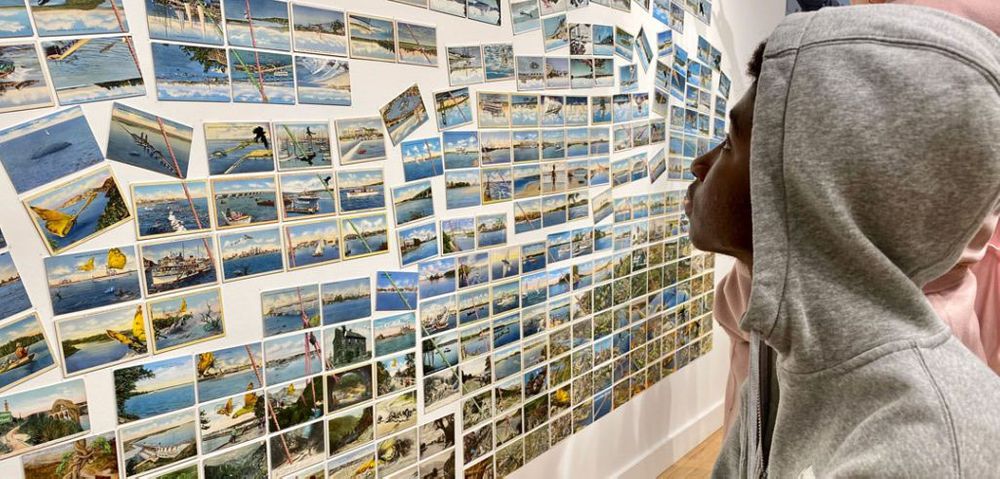 Emmanuel Okeke, explores the postcard display from artist David Opdyke at the Climate Museum Pop-Up. Photos by Kelly Prinz
