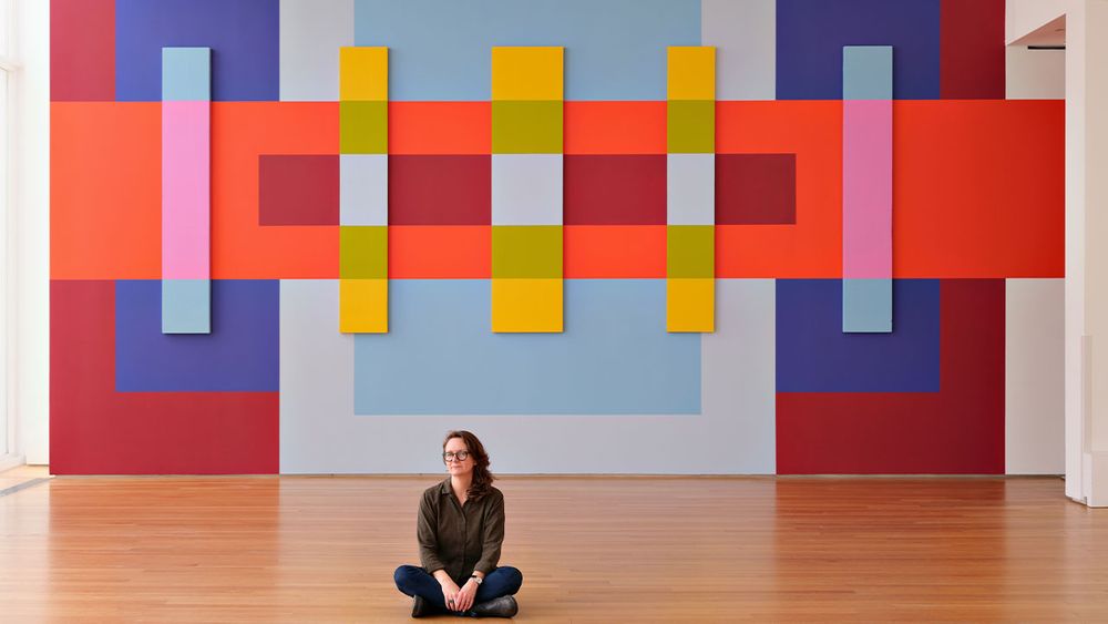 Martha Clippinger seated in front of her installation, titled Through Line, at the North Carolina Museum of Art. Photo by Alex Boerner