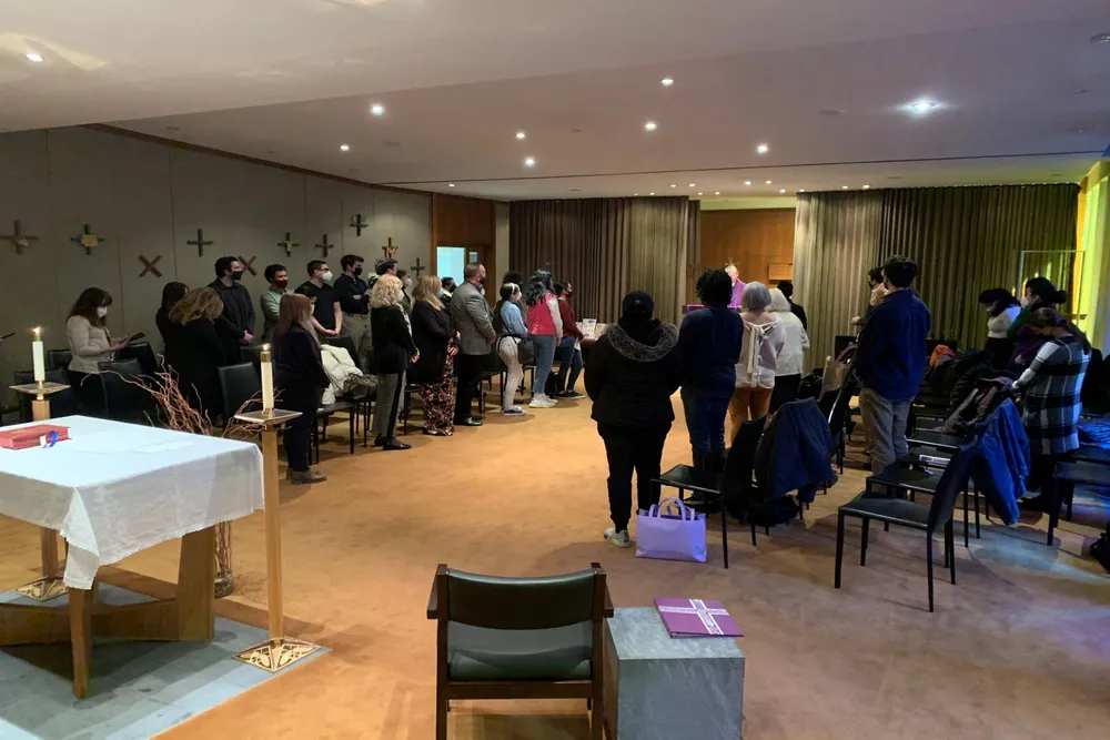 A group of people standing at Mass at Lincoln Center chapel during the gospel.