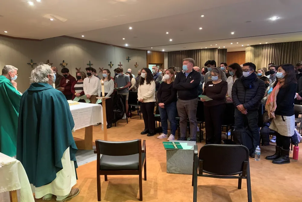 Parents and students standing together facing the alter at chapel in Lincoln Center campus watching two priests in front of the chapel.