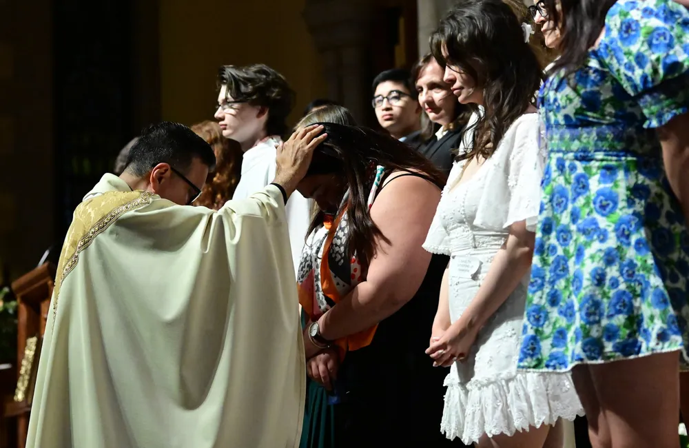 As RCIA candidates stand in from of the University Church as a group, the priest touches the head of a candidate as a blessing.