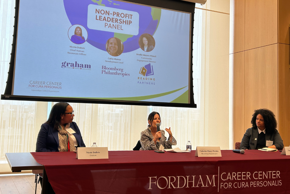 President's Council member speaking on a panel with two other people in front of a projector screen