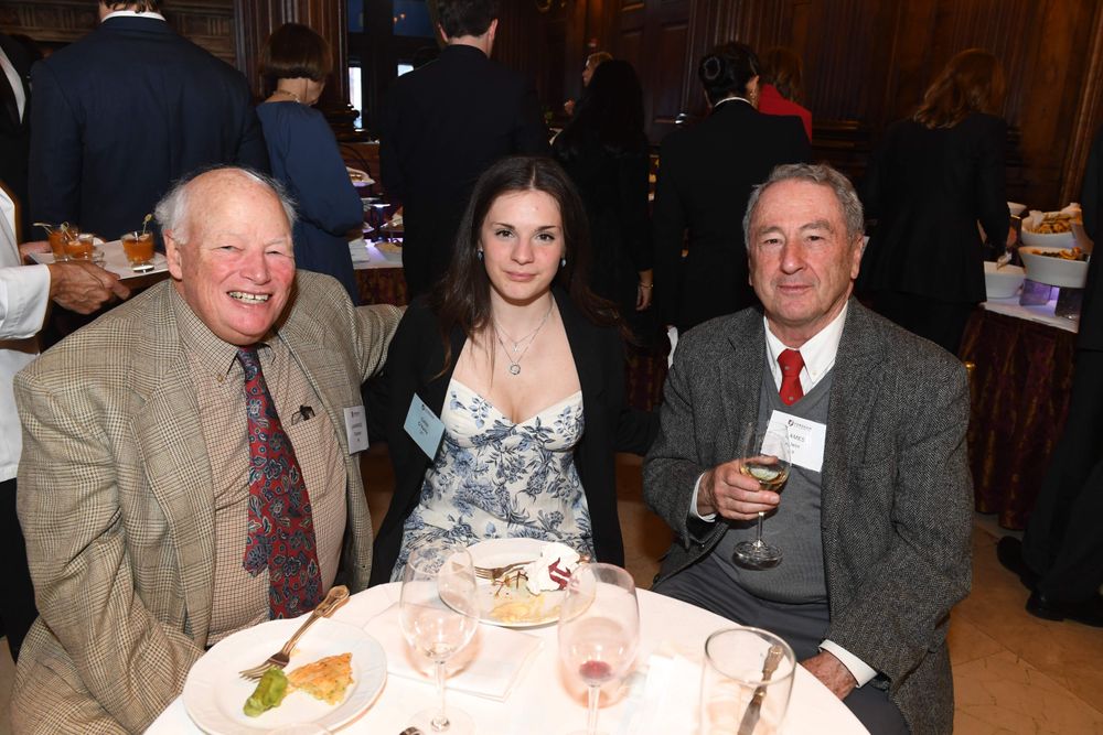 two male donors on sit on either side of a female scholar