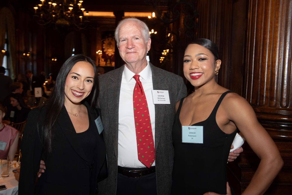 two female students stand on either side of male donor
