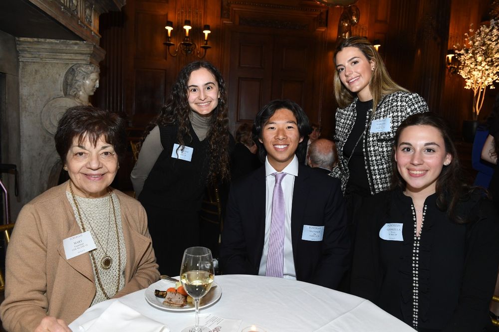 A dark-haired female donor sits with three female students and one male student at the Scholarship Donors and Recipients Reception