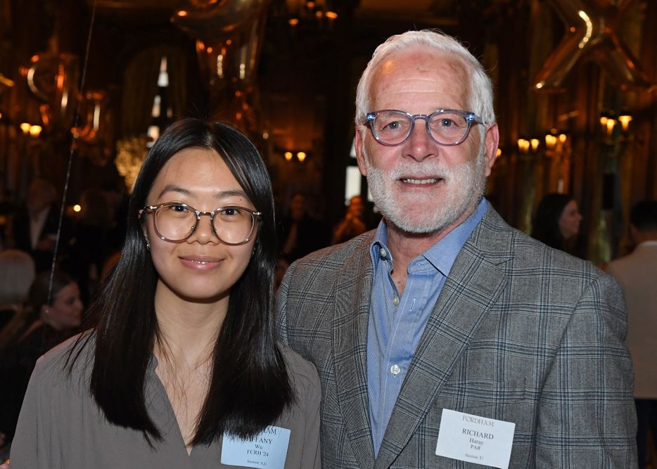 A female, Asian student standing next to a white-haired male donor at the Scholarship Donors and Recipients Reception
