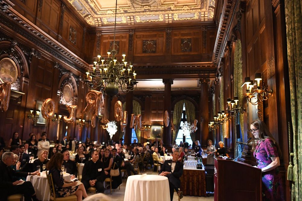 A female donor speaking at a podium looking out to a room full of donors and students at the Scholarship Donors and Recipients Reception
