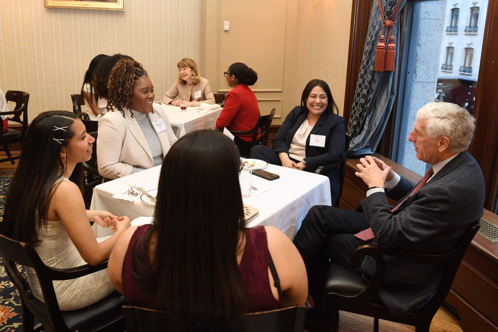 group of students sitting at tables, conversing with donors