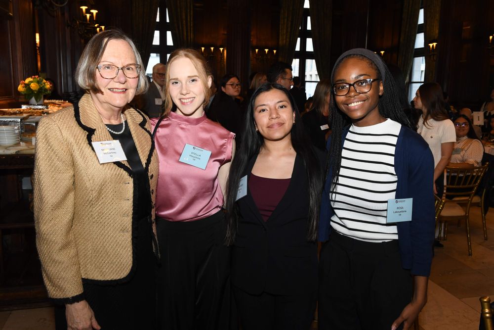 female donor stands beside 3 female students