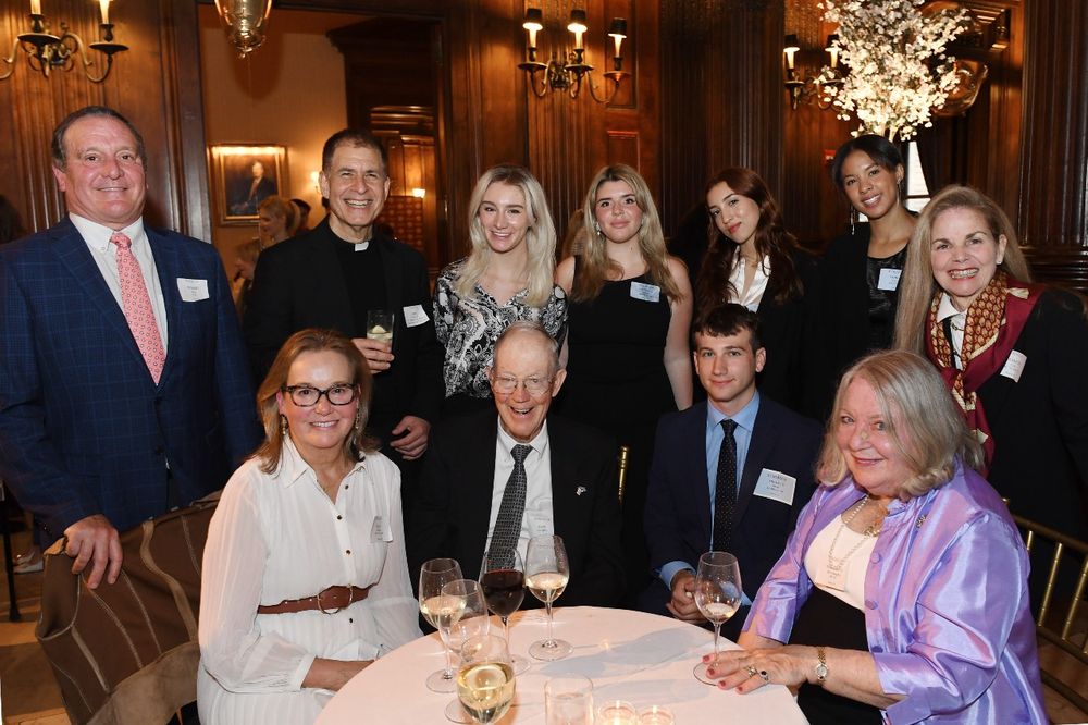 5 Marymount College Donors pose with a priest and a group of 4 female students and a male student at the Scholarship Donors and Recipients Reception