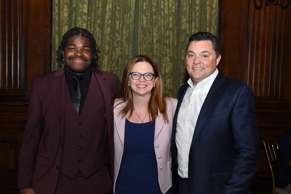 male student in maroon suit with president of the University and male donor
