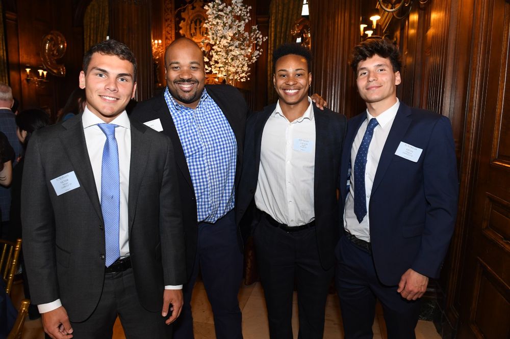 Three male students pose with a male donor at the Scholarship Donors and Recipients Reception