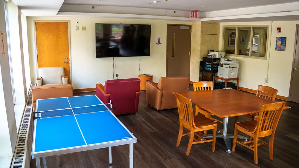 Recreation room with mounted flat screen TV, loungers, ping pong table and additional tables and chairs