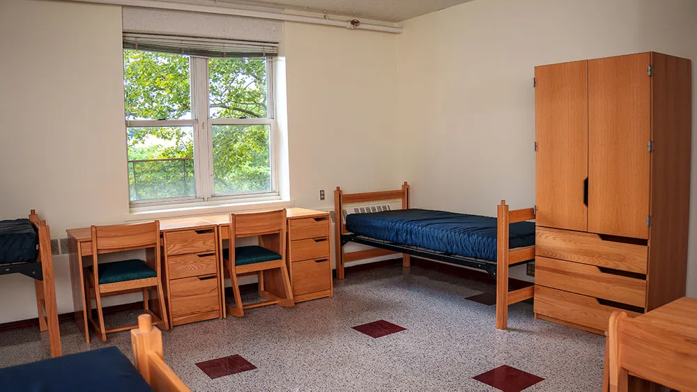 Angled view of a triple with a view of desks, beds and wardrobe