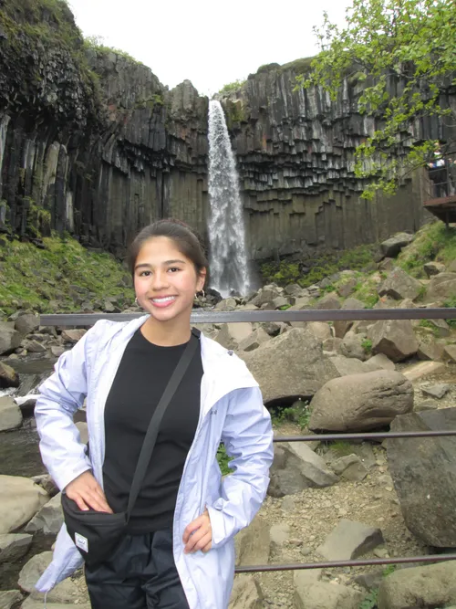 A student standing in front of a waterfall