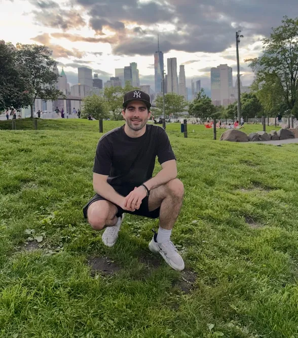A student crouched down in a field outside