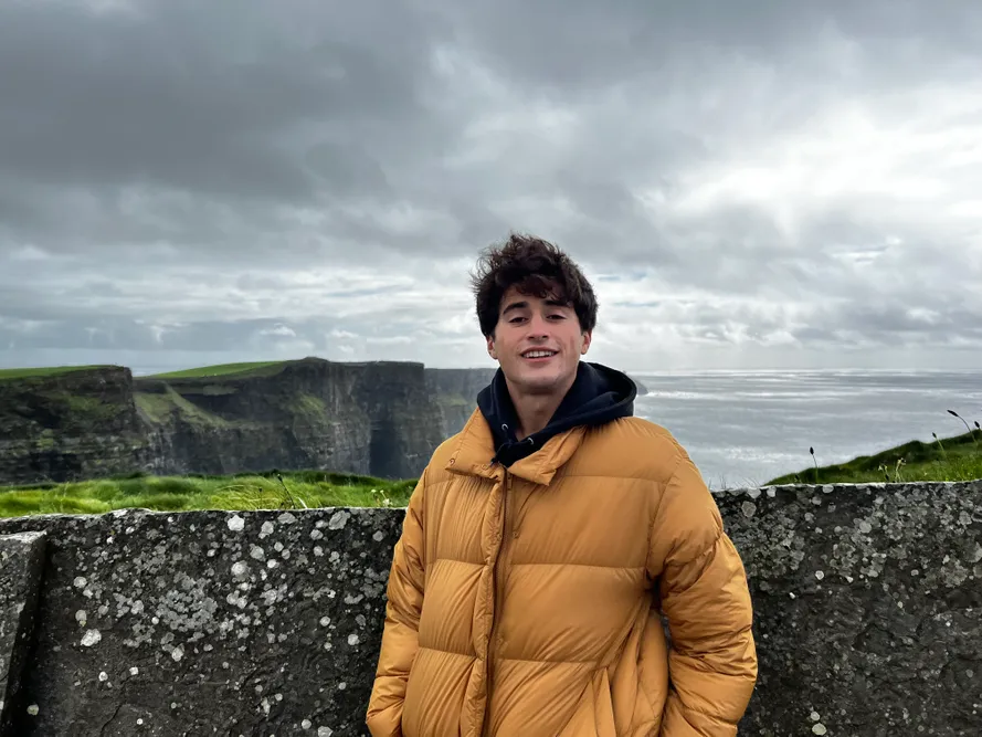 Student standing in a coat in front of a landscape