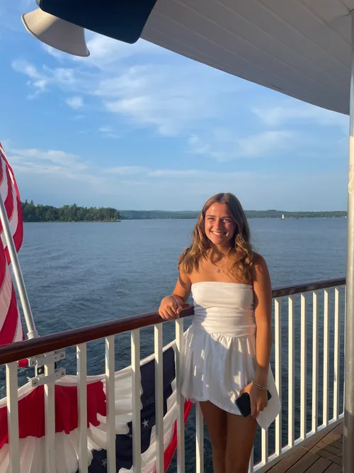 Student standing in front of a fence overlooking a body of water