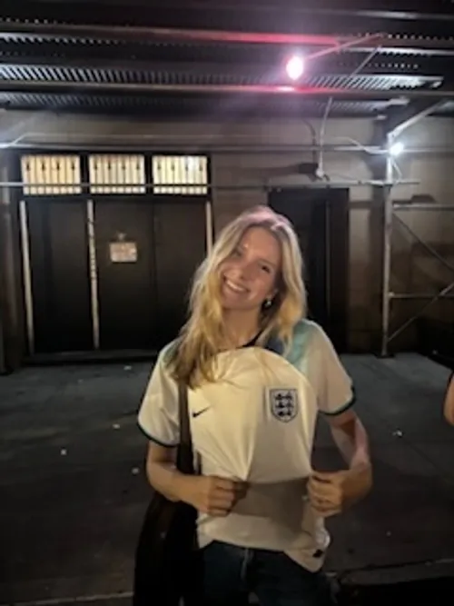 A student standing and emphasizing their football jersey
