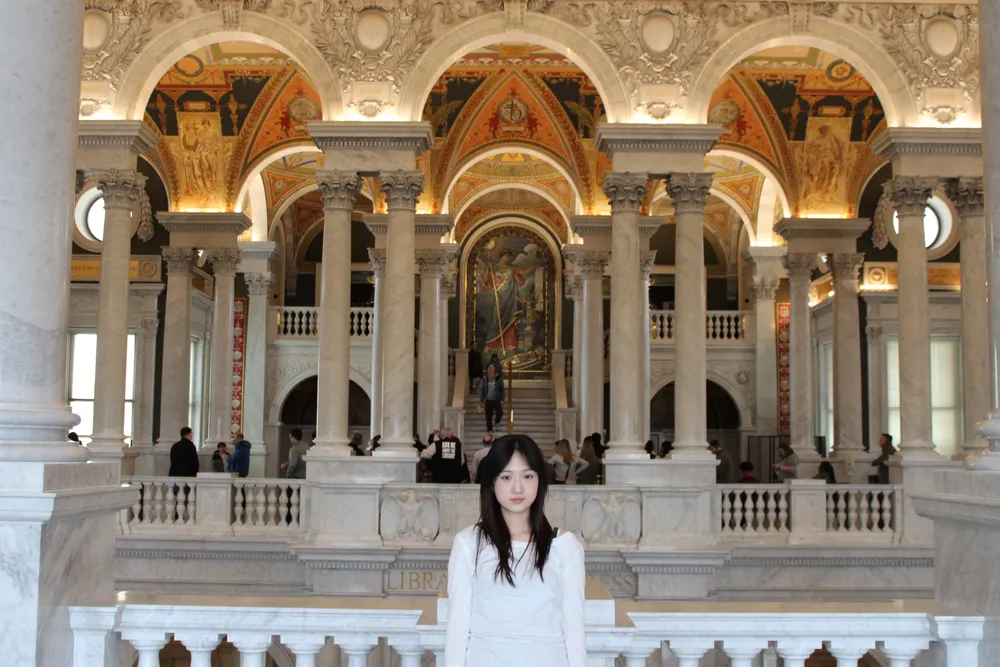 Student standing in a coat at the beach