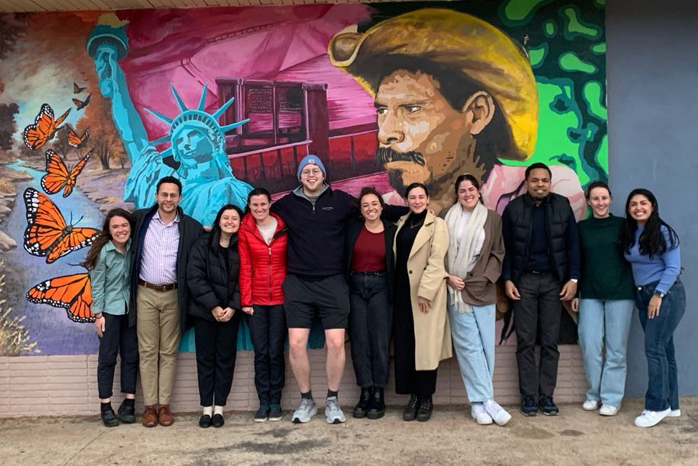 A group of adults standing in front of a wall mural.