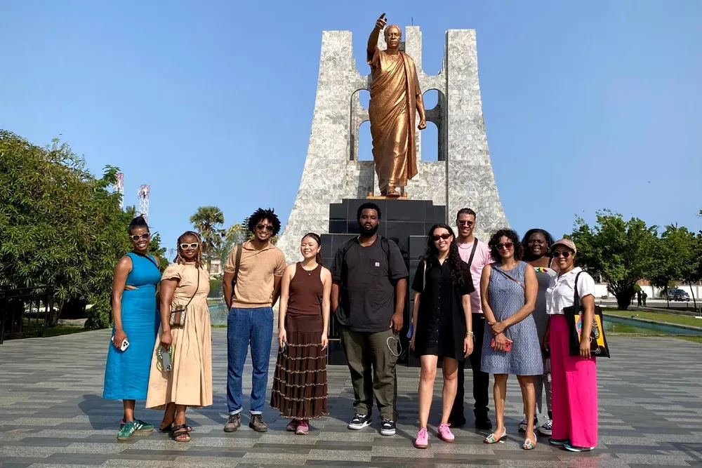students and staff in front of a gold statue