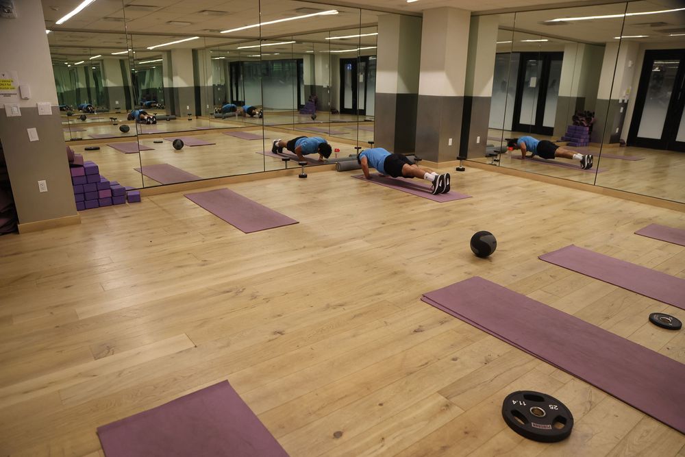 A student holds a plank on a mat in the aerobics room of the RamFit Center