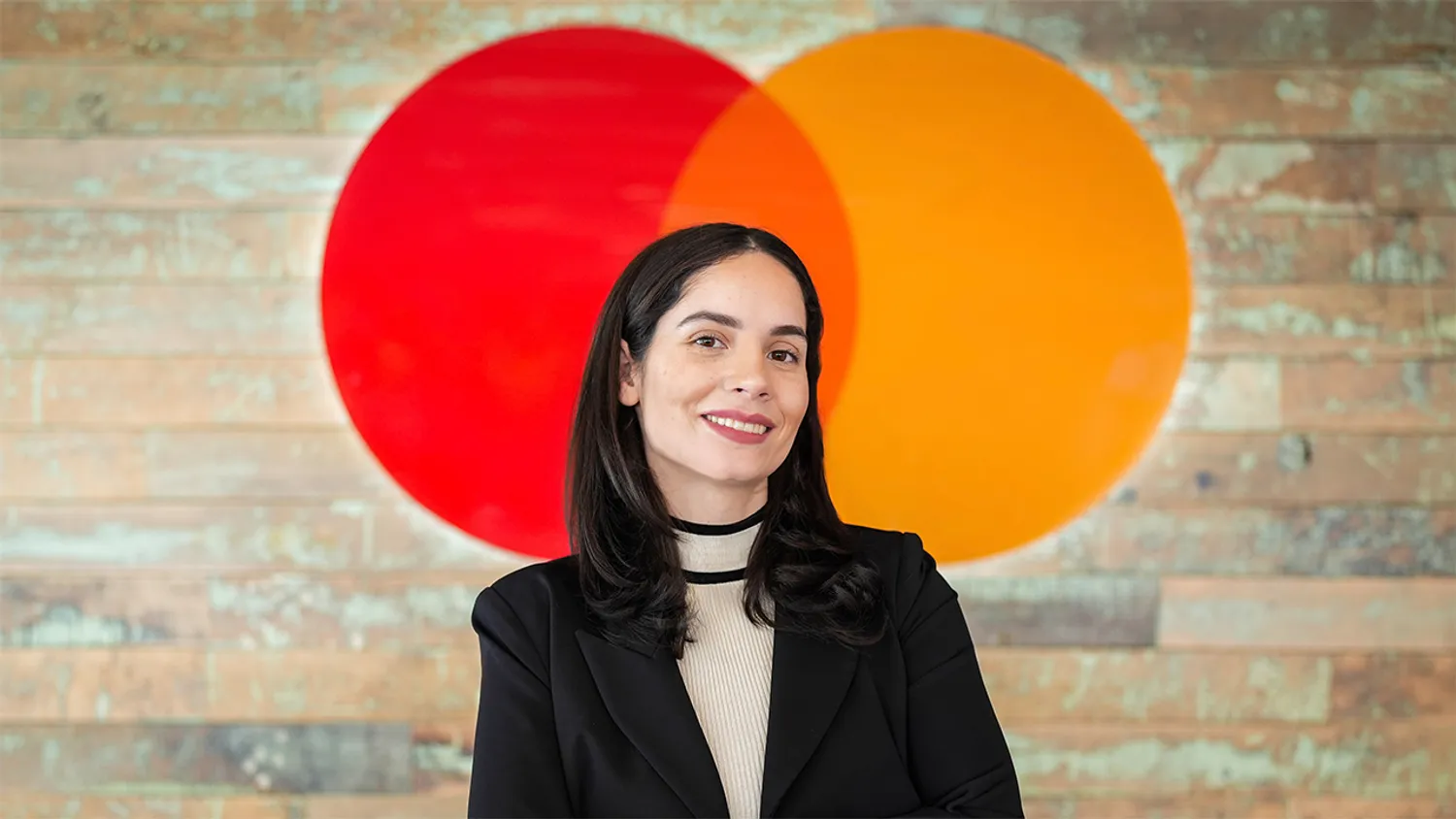 Indhira Jaquez-Torres Mastercard headshot posing in front of logo