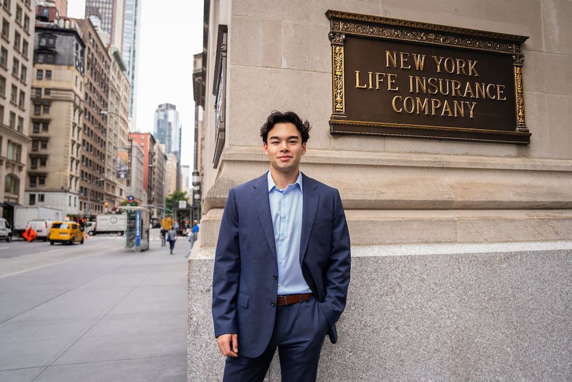 Fordham Class of 2026 student, Theo Vandenberg, in front of the New York Life Insurance Building