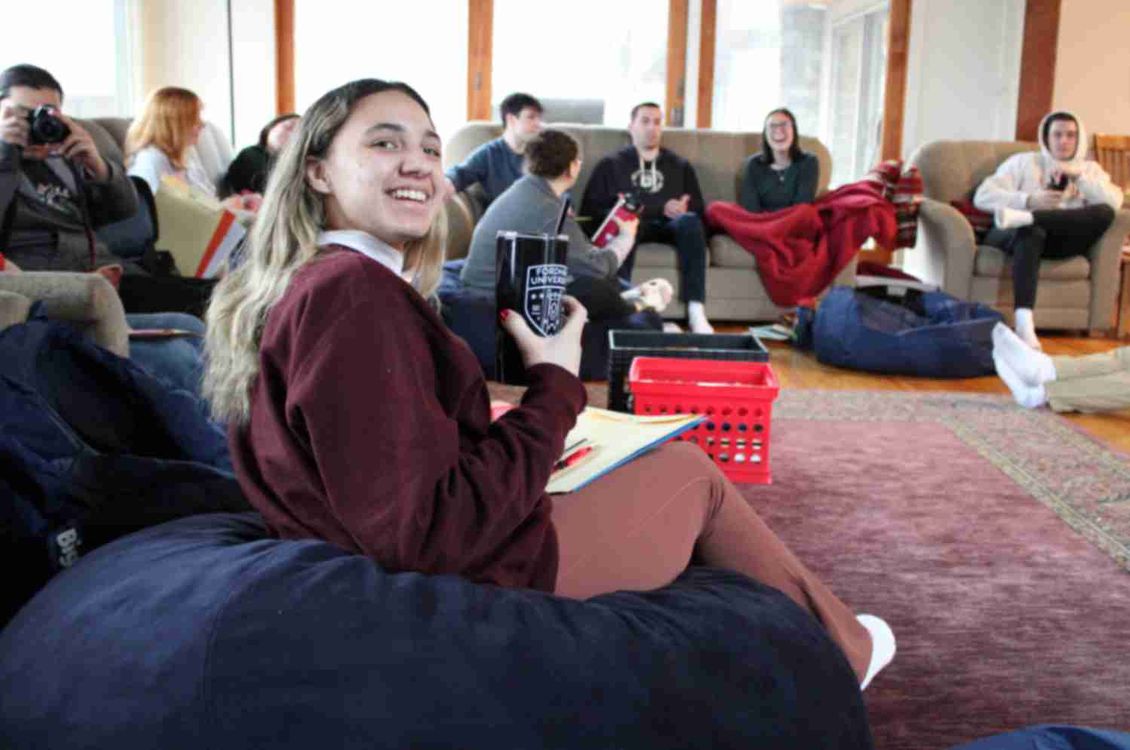 Student holding a mug smiling with retreatants in the background