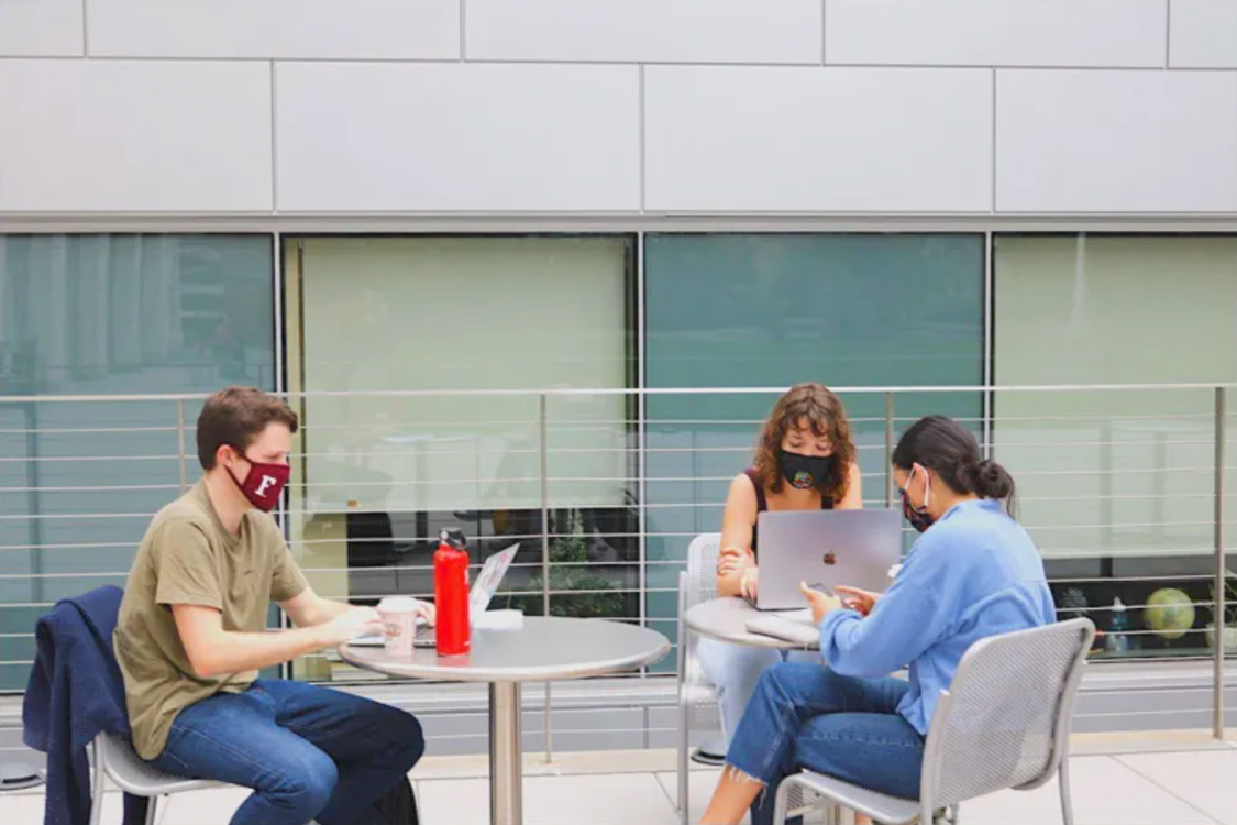 Three students study on their laptops outside at the Lincoln Center campus.