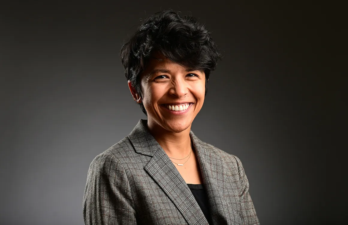 A woman with short hair wearing a patterned blazer and black top.