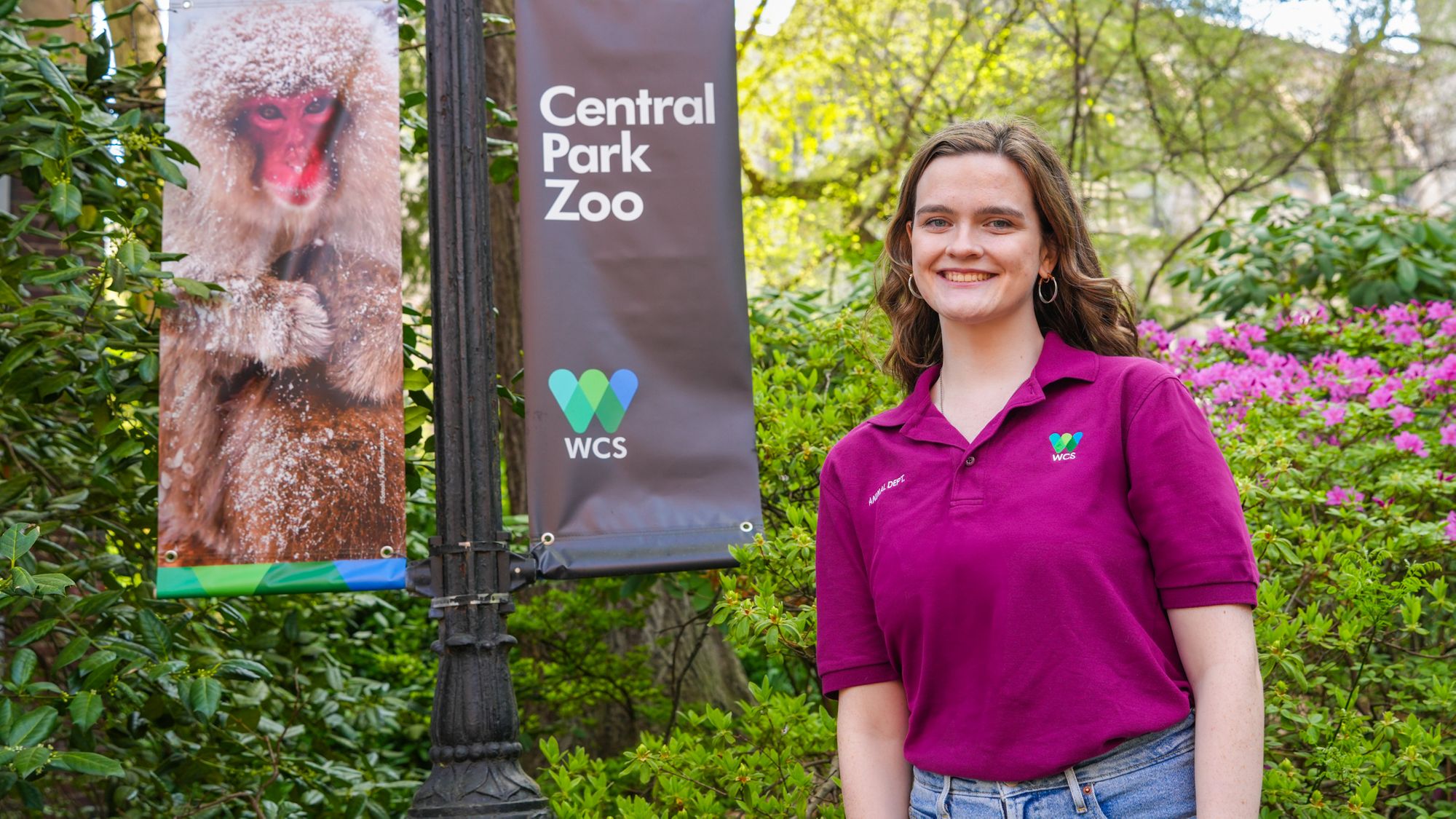 A student standing next to a Central Park Zoo/monkey sign