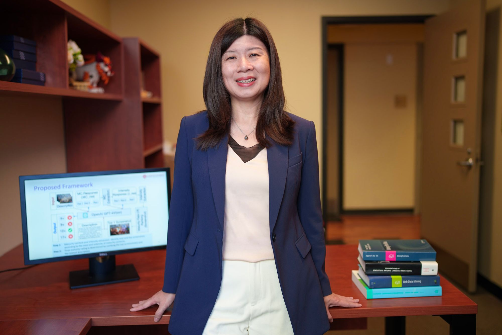 Yilu Zhou stands in front of her desk in her office