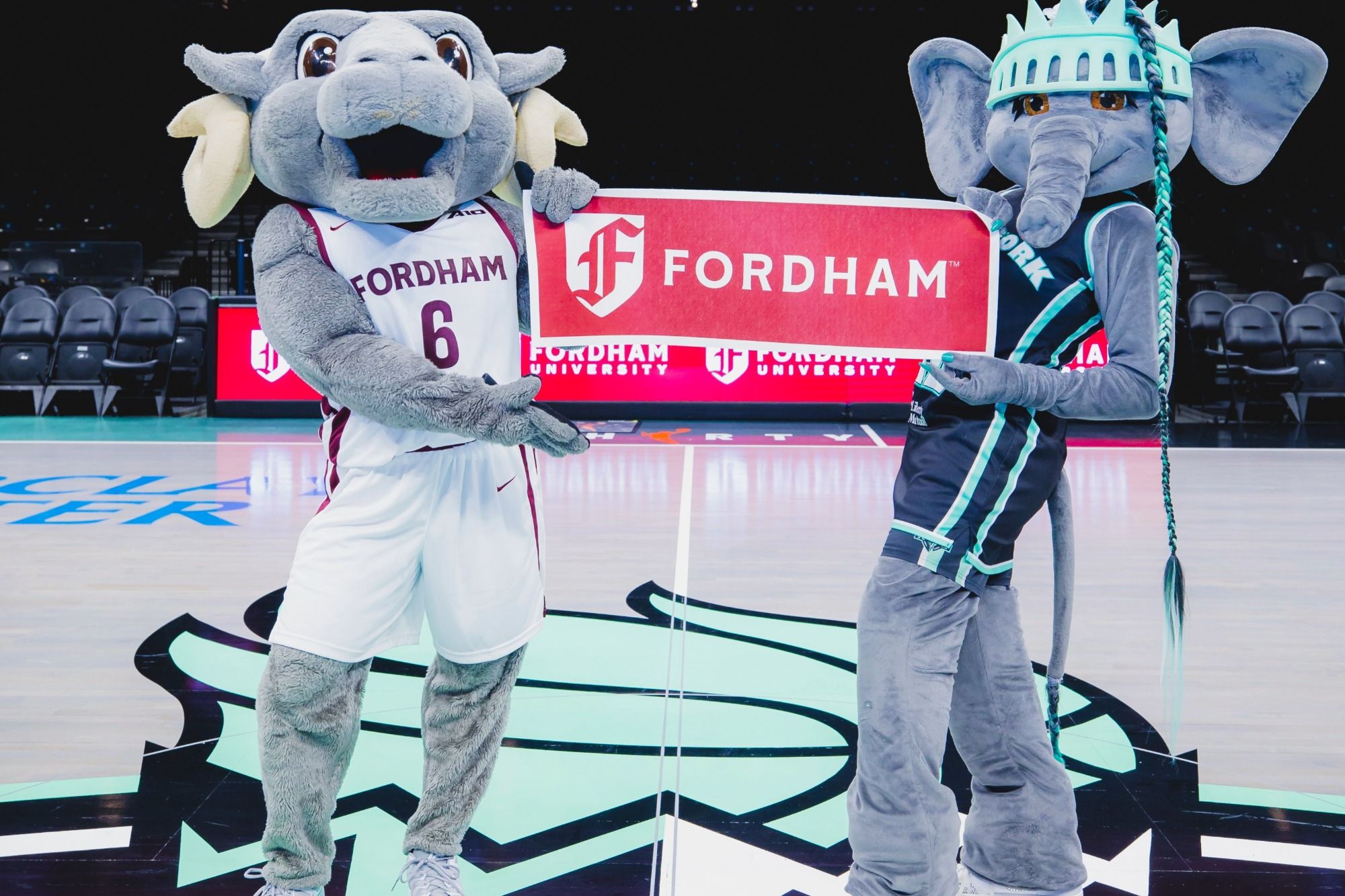 Ramses and Ellie post together on the NY Liberty court with a Fordham banner