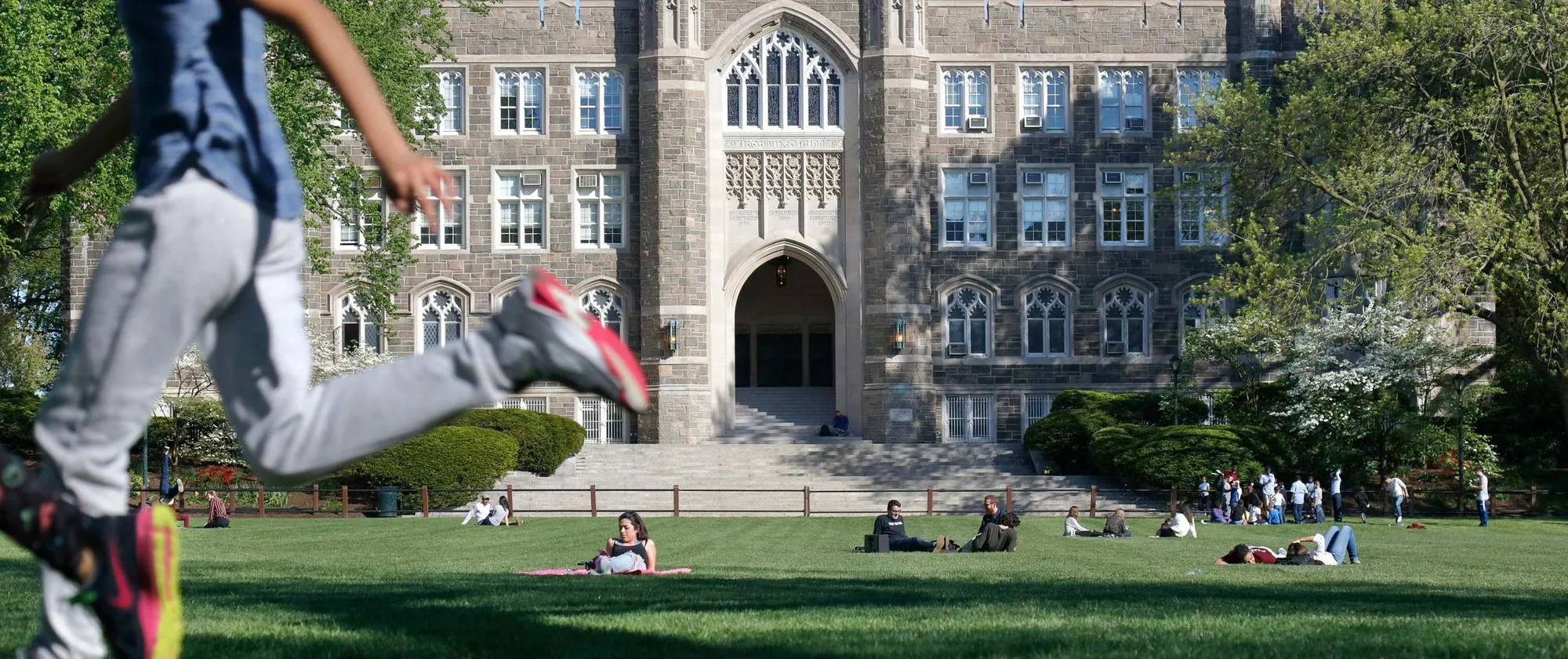 Students relax and unwind in the grass in front of Keating Hall on the Rose Hill campus