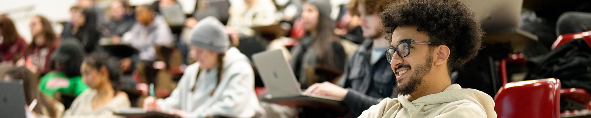 Male student smiles while attending a lecture